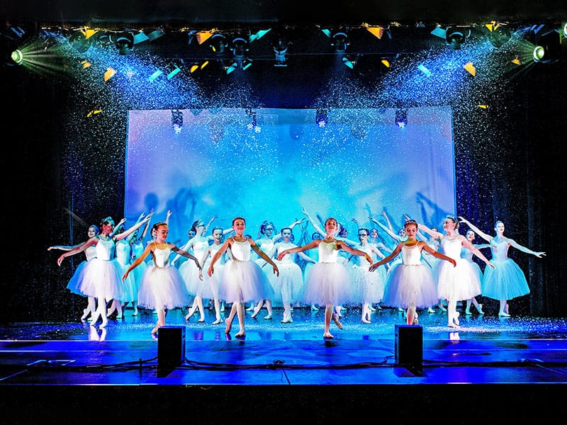 dance school show group of dancers on stage in white costume with snow effect dance photographer in Edinburgh